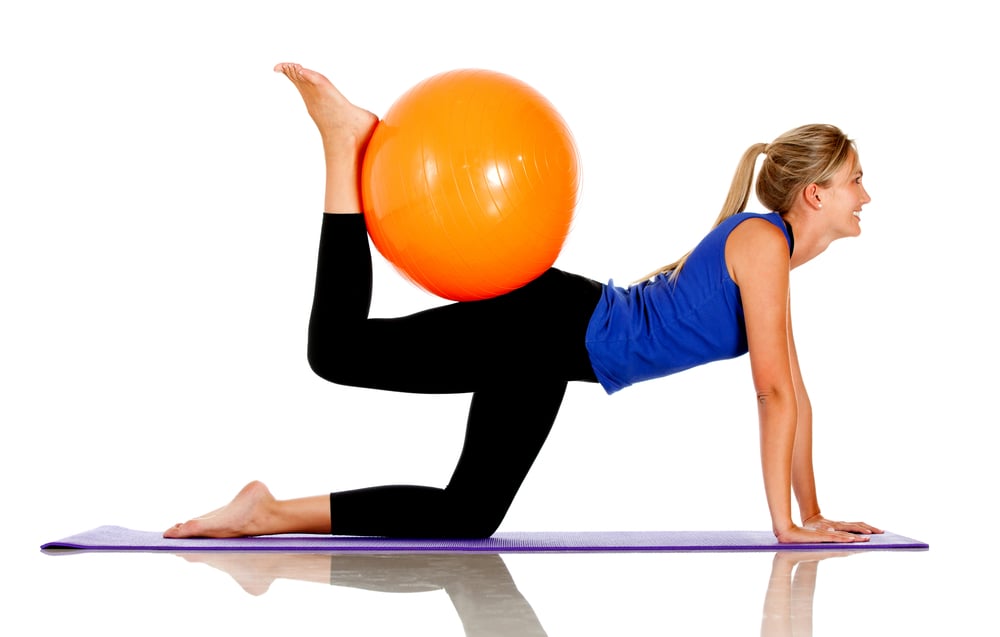 Sportive woman exercising with a Swiss ball - isolated