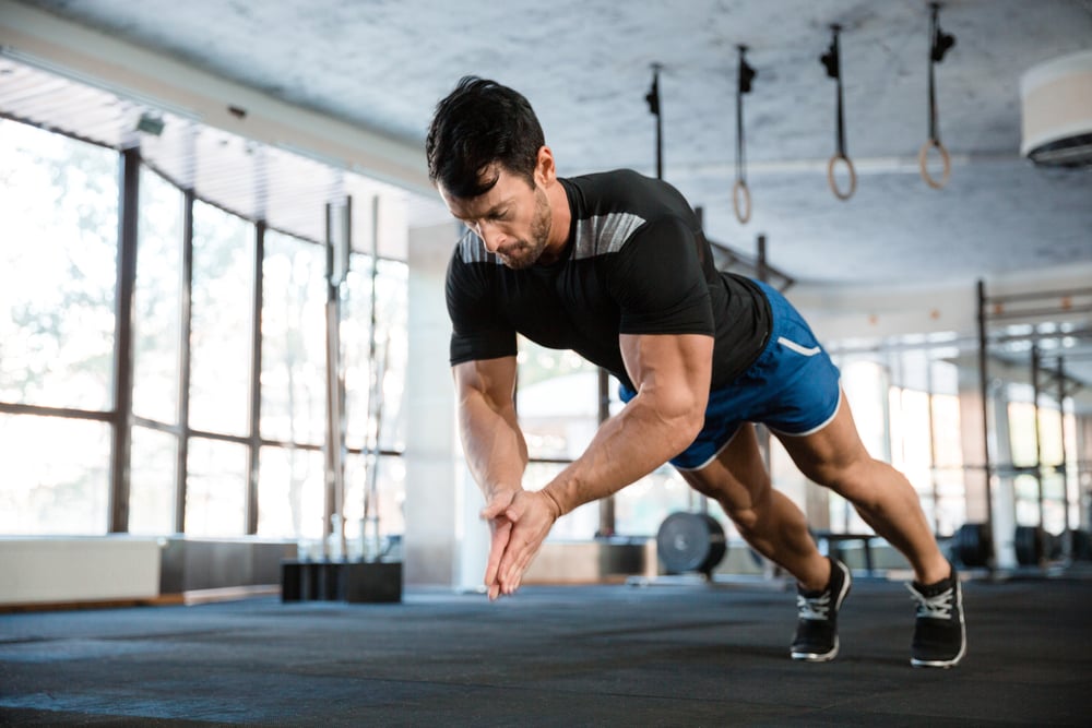 Sportsman wearing blue shorts and black t-shirt doing push-up with claping