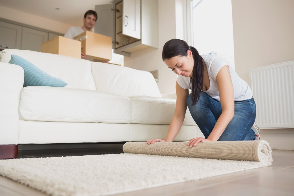 Two young relocating people moving into their house and furnishing the lounge