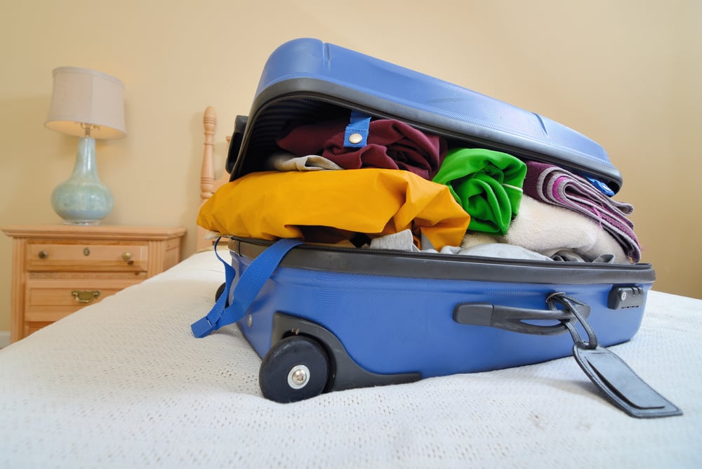 overflowing luggage on a bed